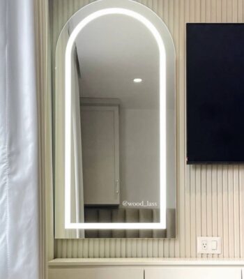 Espejo arqueado con iluminación frontal encendida montado en pared de listones beige - Cleopatra Glam | Woodlass Ecuador