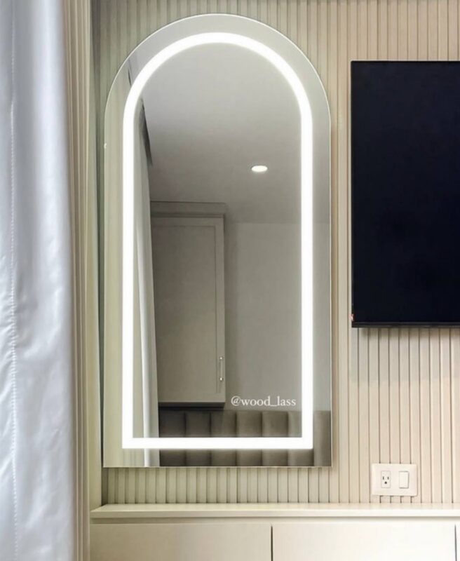 Espejo arqueado con iluminación frontal encendida montado en pared de listones beige - Cleopatra Glam | Woodlass Ecuador